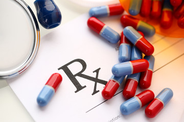 Pile of pills fall out from jar to paper list closeup