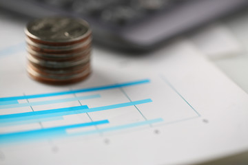 Pile of silver coins stand at financial graph papers