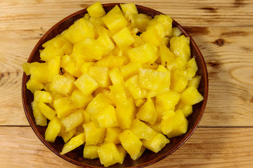 Diced pineapple in a plate on wooden table. Top view