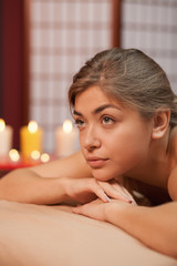Naklejka premium Vertical close up of a beautiful blond haired woman looking away dreamily, relaxing at the spa center. Attractive young female enjoying aromatherapy at massage center. Skin, body, health concept