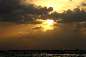 sunset at sea, red sun sits behind the horizon