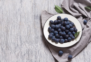 Blue plum berries in metallic bowl on a table