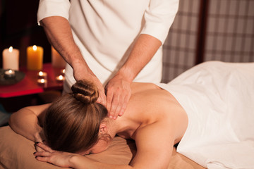 Fototapeta na wymiar Woman receiving soothing neck massage at spa center. Professional male masseur massaging neck of female client. Woman enjoying spa treatment at the luxurious hotel. Recreation, relaxation concept