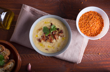 Lentil soup puree with bacon in a bowl on a dark wooden background