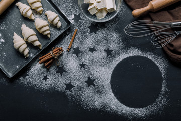 top view of tray with croissants, ingredients and whisks on table covered by flour with symbols of...