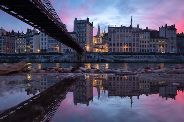 Old bridge over the Saone river reflected in a puddle during a pink sunset in Vieux-Lyon, Lyon.