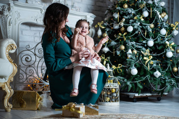 Merry Christmas and happy holidays. Mother and daughter having fun near the Christmas tree with gifts