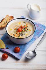 Lentil soup puree with tomatoes, cucumber and nuts in a bowl on a white wooden background