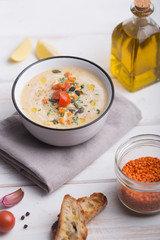 Lentil soup puree with tomatoes, cucumber and nuts in a bowl on a white wooden background