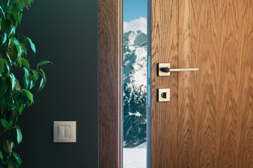 Alpejskie góry za półotwartymi drzwiami. Drewniane drzwi w pięknym wnętrzu - 235867442