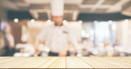 Empty Wood table top with Chef cooking in restaurant kitchen blurred defocused background