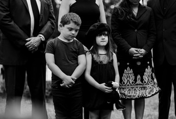 Obraz premium Sad grandkids standing by the grave