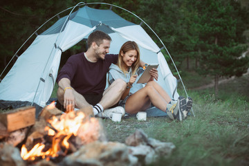 Smiling young couple using tablet computer on a camping 