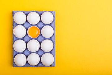 White eggs and egg yolk on the yellow background with copy space