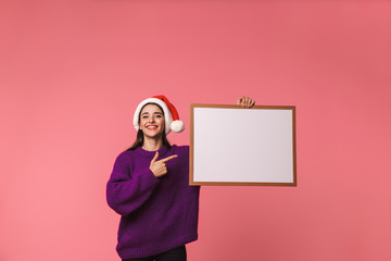 Beautiful happy young emotional woman posing isolated over pink background holding copyspace blank.