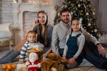 Christmas photo of happy family with gift boxes on background of decorated Christmas tree. Family celebrates New year