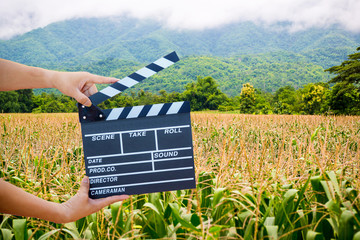 Man hands holding movie clapper isolated on nature background. Shown slate board. use the colors...