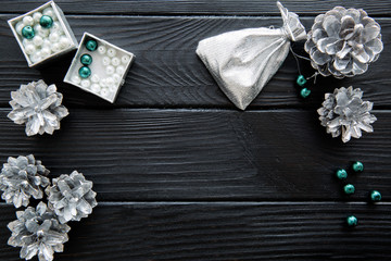 Silver cones and emerald green beads on black table. Space for text.