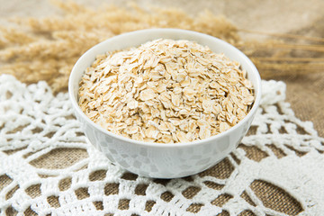 Oatmeal in white bowl with spikes on textile background. Healthy eating