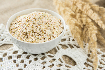 Oatmeal in white bowl with spikes on textile background. Healthy eating