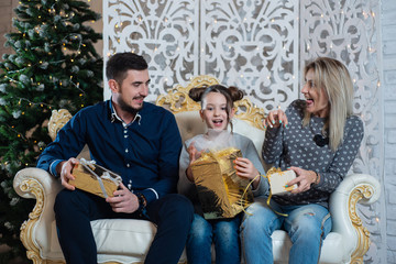Christmas photo of happy family with gift boxes on background of decorated Christmas tree. Family celebrates New year