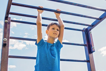 Kid training on a climbing frame in playground outdoors