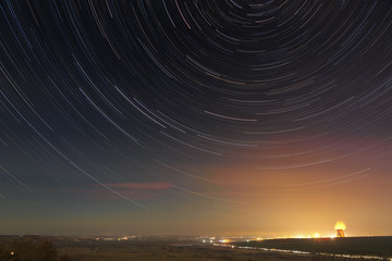 Star trails in the night sky. A view of the starry space in the background of the city illumination.