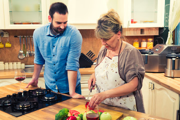 Mature woman and her son preparing food in the kitchen.