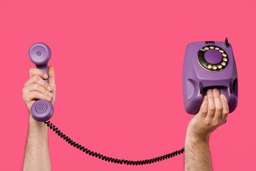 cropped shot of man holding purple rotary phone isolated on pink