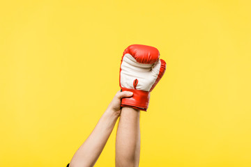 cropped shot of woman holding man hand in boxing glove isolated on yellow