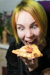 Shocked woman with mad eyes bites pizza.