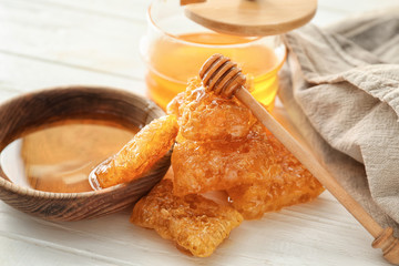 Sweet honey with pieces of fresh combs on white wooden table