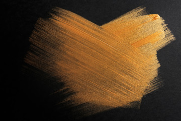 Strokes of gold paint on dark background