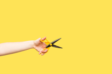 cropped shot of person holding scissors isolated on yellow