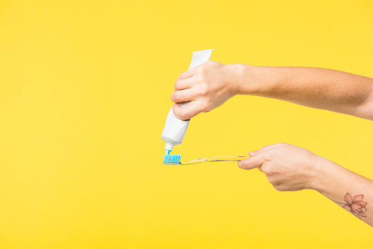 Cropped Shot Of Person Holding Toothbrush And Toothpaste Isolated On Yellow