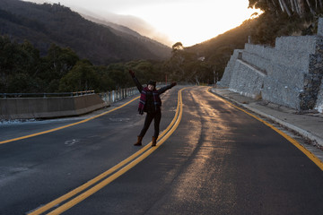 Young woman posing on the road at the crack of dawn with a beautiful sunrise