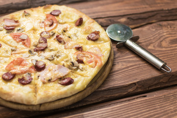 Pizza and knife for cutting in a cardboard box on a dark wooden background.