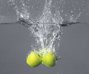 Falling of apples into water on grey background