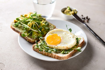 Tasty toasts with avocado and fried egg on plate