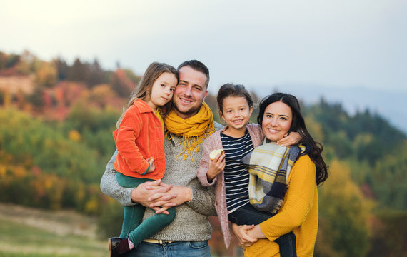A portrait of young family with two small children in autumn nature.