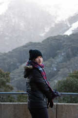 Fototapeta na wymiar Young woman posing in front of snow covered Mount Kosciuszko at Thredbo