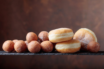Sweet donuts powdered with sugar on a brown background.