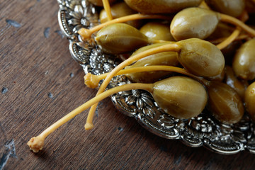 Pickled caper berries in metal dish .