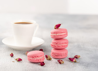 Pink macaroons with dried flower buds and cup of coffee. Pastel colored.