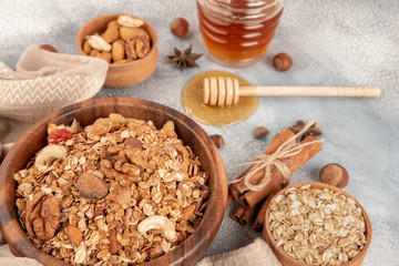 Homemade granola in wooden bowl with ingredients - oat, nuts, honey and spice cinnamon and anise