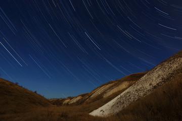 Star trails in the night sky. A view of the starry space in the background of the hills.