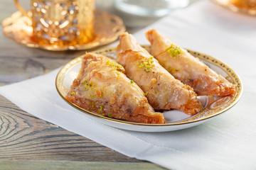 Traditional arabic dessert baklava with cashew, walnuts and cardamom with an eucalyptus branch on a wooden table