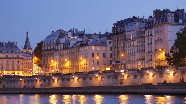 View on the Seine river, in the night. Filmed in the saint-michel disctrict in the center of Paris, France. People are walking on the quays.