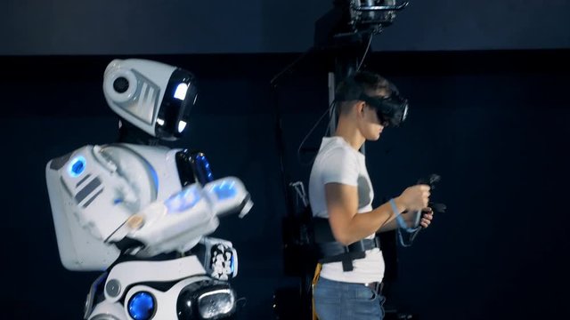 Droid and man moving in VR equipment, side view.