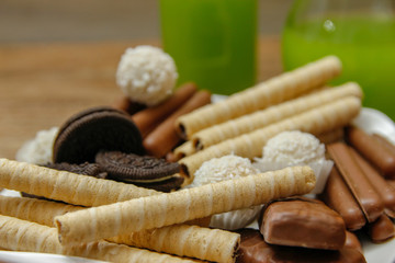 Different cookies on a plate and green apple and kiwi juice. Wooden table and rustic background
